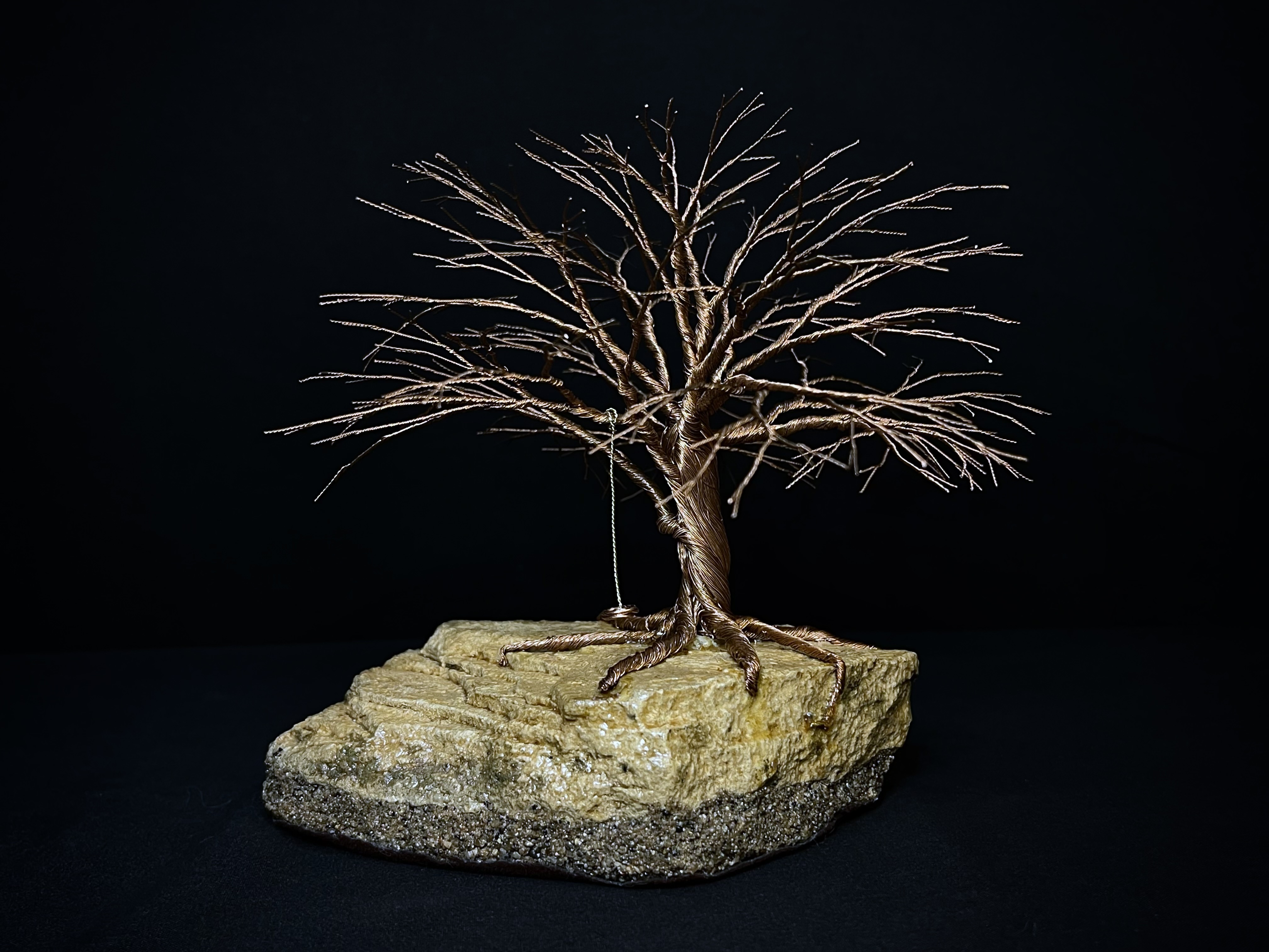 Wire tree with a swing rooted over a natural stone base
