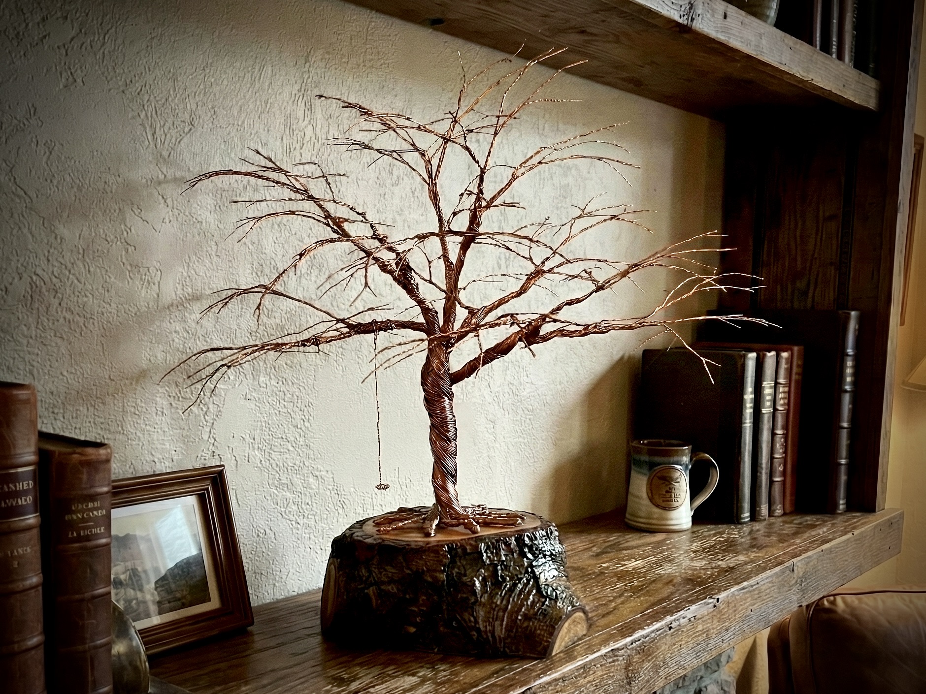 A finished Forest of Wire sculpture displayed on a warm wooden bookshelf